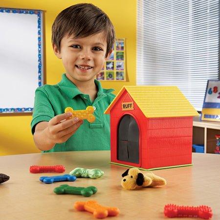 Child playing with educational doghouse toy, colorful bones, and plush dog for sensory learning