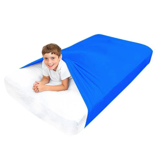 Child in blue sensory compression sheet on white mattress, sensory-friendly bedding for kids
