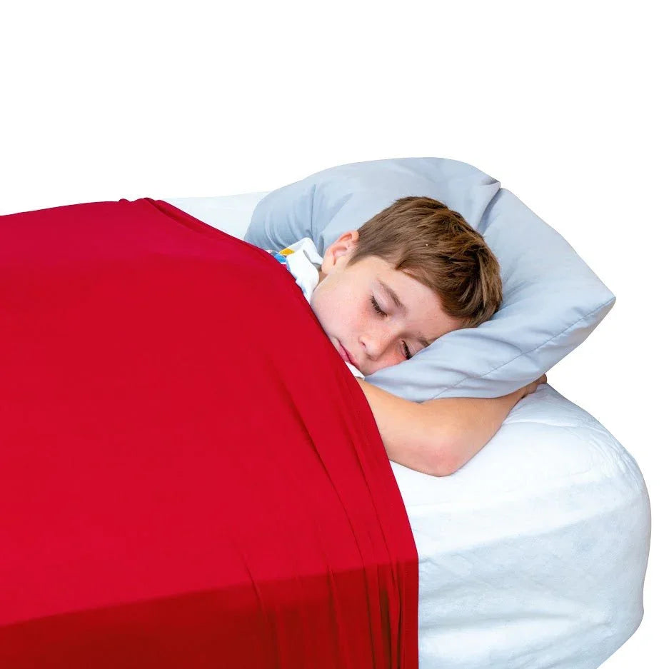 Child sleeping under a red sensory compression sheet on a bed with a gray pillow.