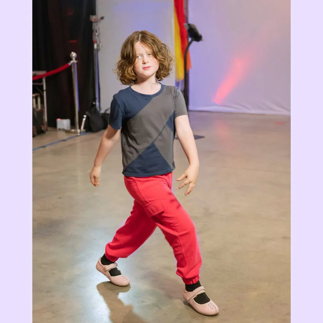 Child wearing sensory-friendly t-shirt and red jogger pants on indoor runway