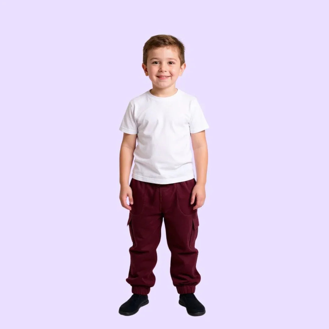 Smiling boy in sensory-friendly burgundy jogger pants and white t-shirt on light background