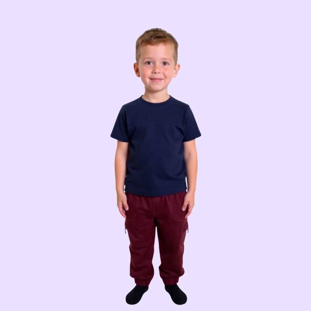 Smiling child in sensory-friendly navy t-shirt and maroon pants on light background