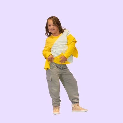 Smiling child in yellow and light blue sensory-friendly shirt, grey pants, beige sneakers