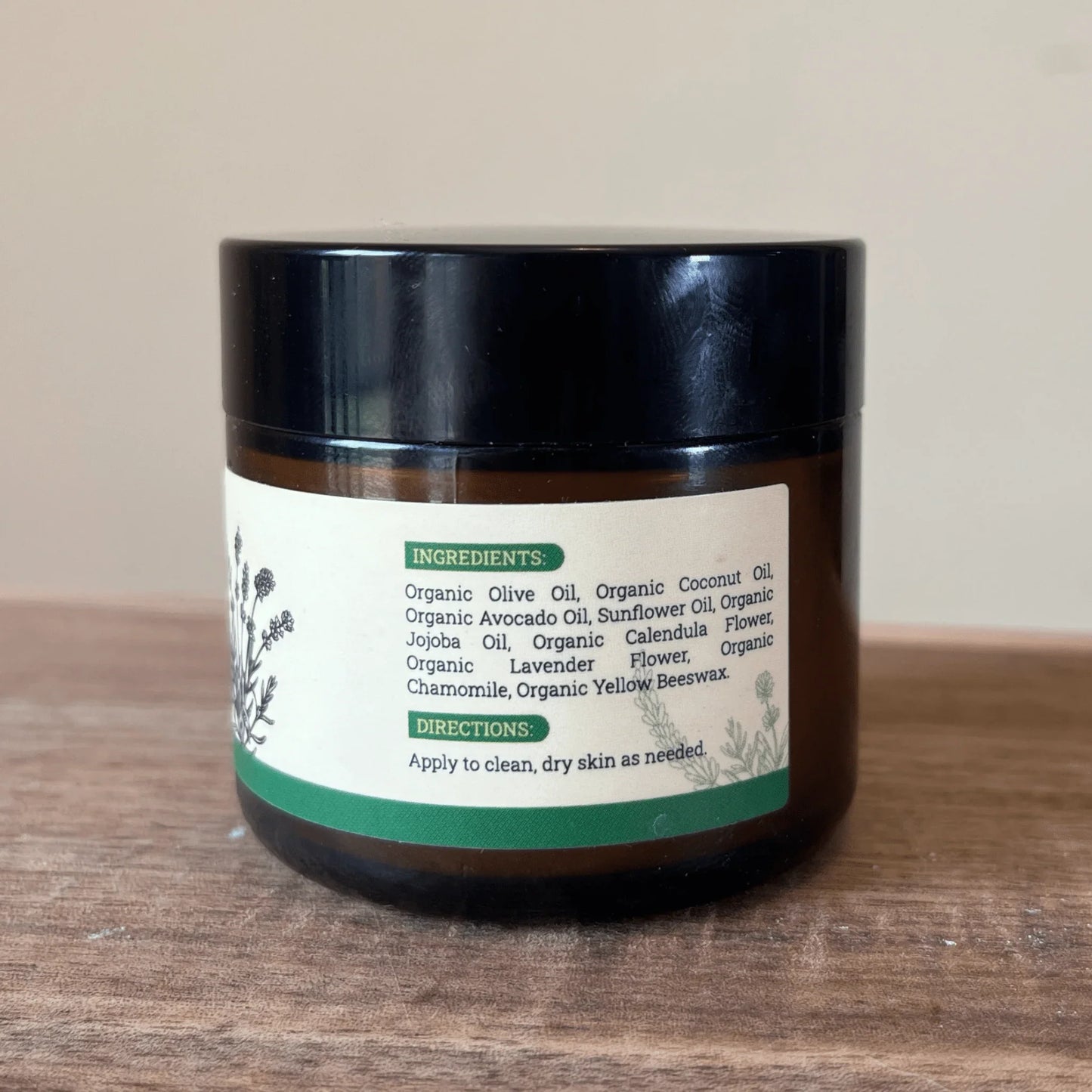 Brown jar of skin healing salve with natural organic ingredients label on wooden surface
