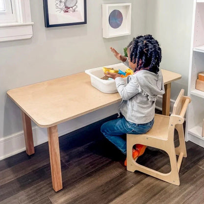 Child playing with sensory bin at wooden table in a learning-friendly room