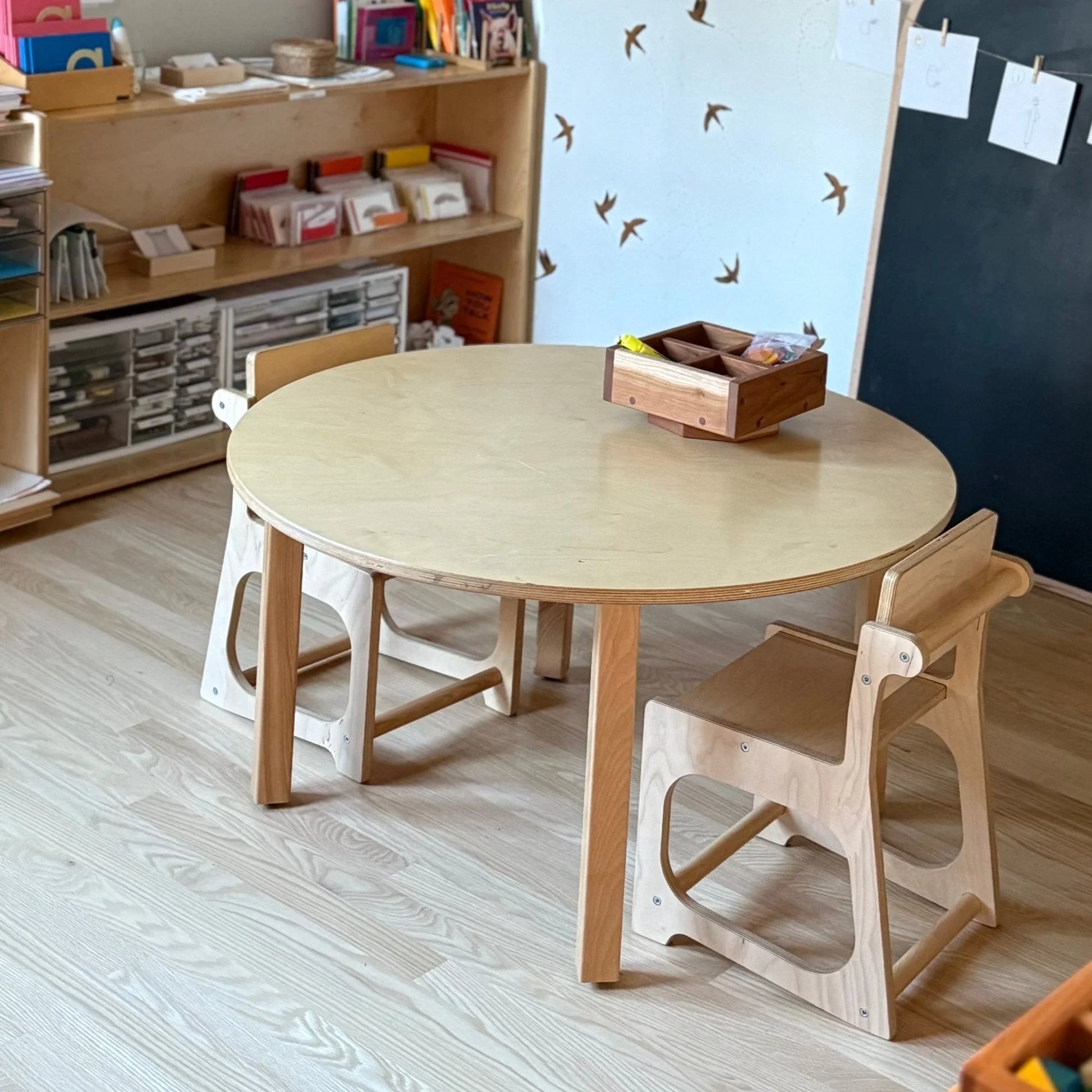 Wooden round sensory table with two kids’ chairs in a classroom setting