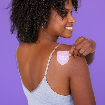 Woman applying a pink patch labeled 'The Friendly Patch' on her shoulder against a purple background