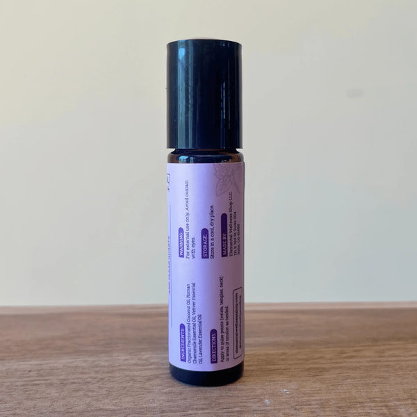Crystal-infused essential oil roller bottle for sleep support on a wooden surface