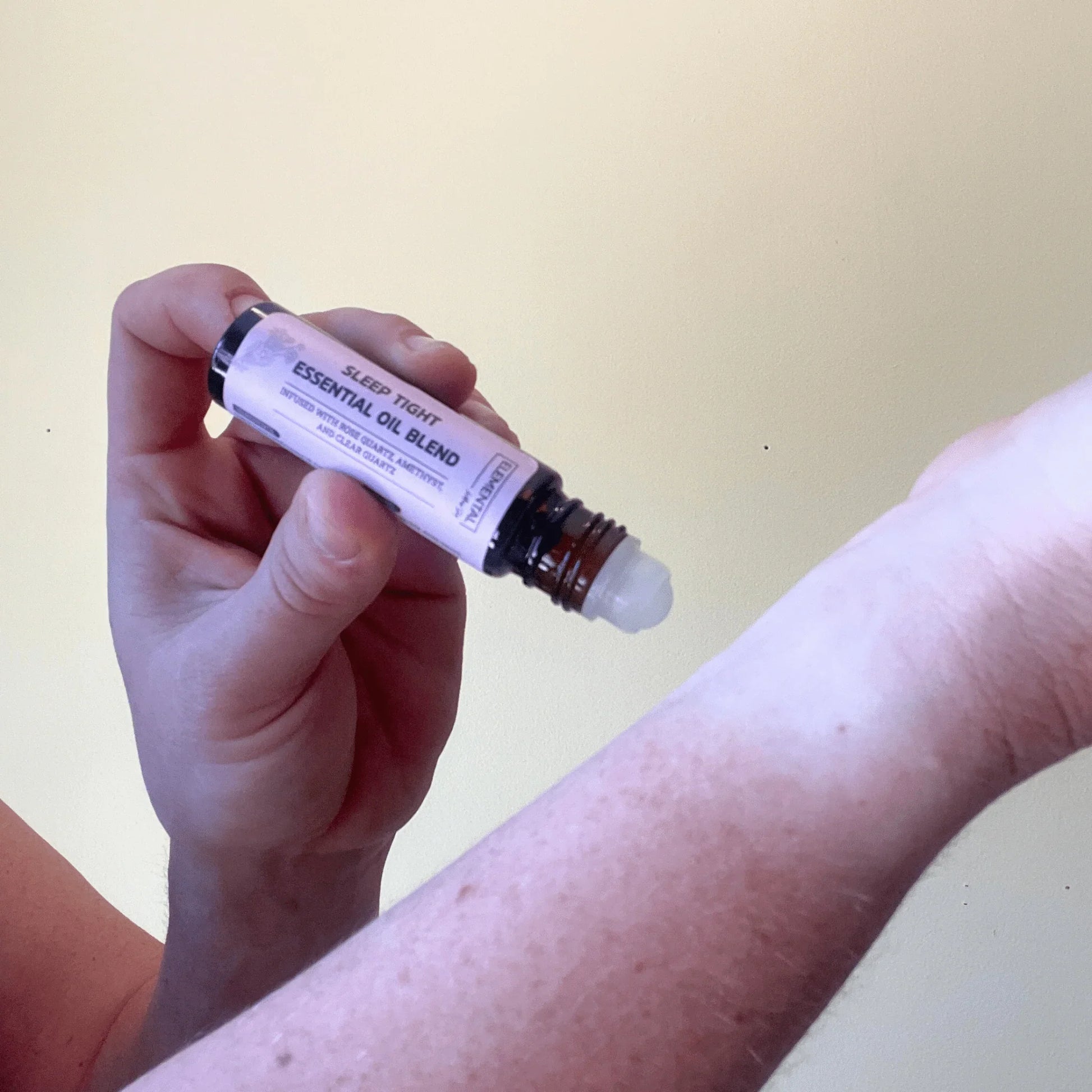 Hand applying Sleep Tight crystal-infused essential oil blend roller to wrist for sleep support