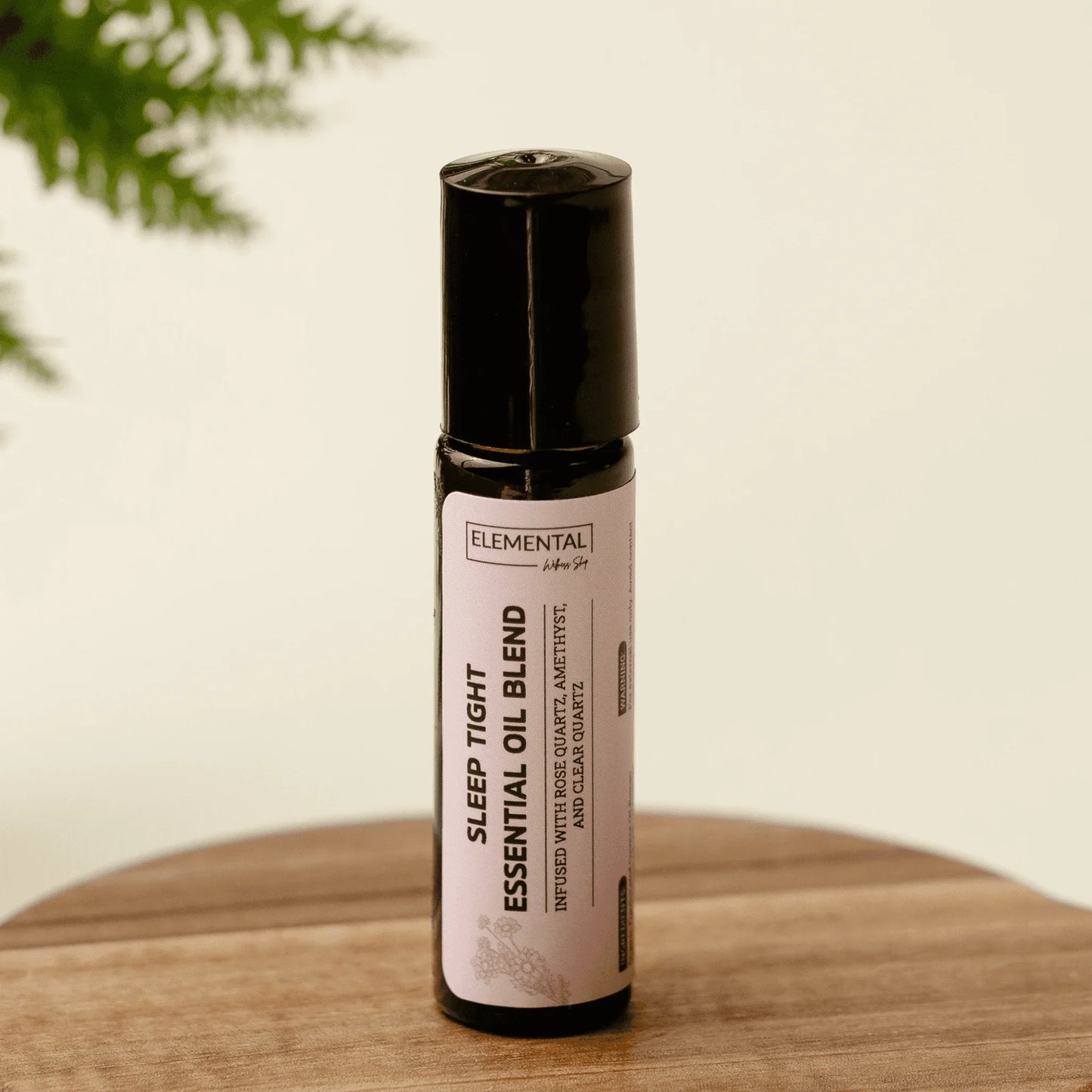 Sleep Tight crystal-infused essential oil blend roller bottle for sleep support on wood table