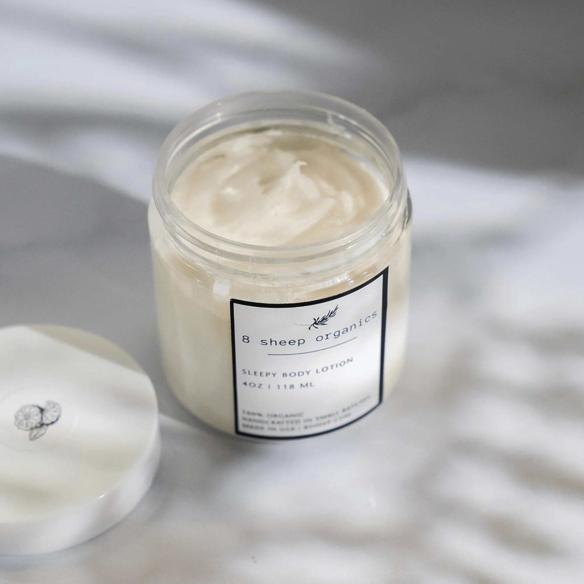 8 Sheep Organics Sleepy Body Lotion jar open on a marble surface, sleep support skincare