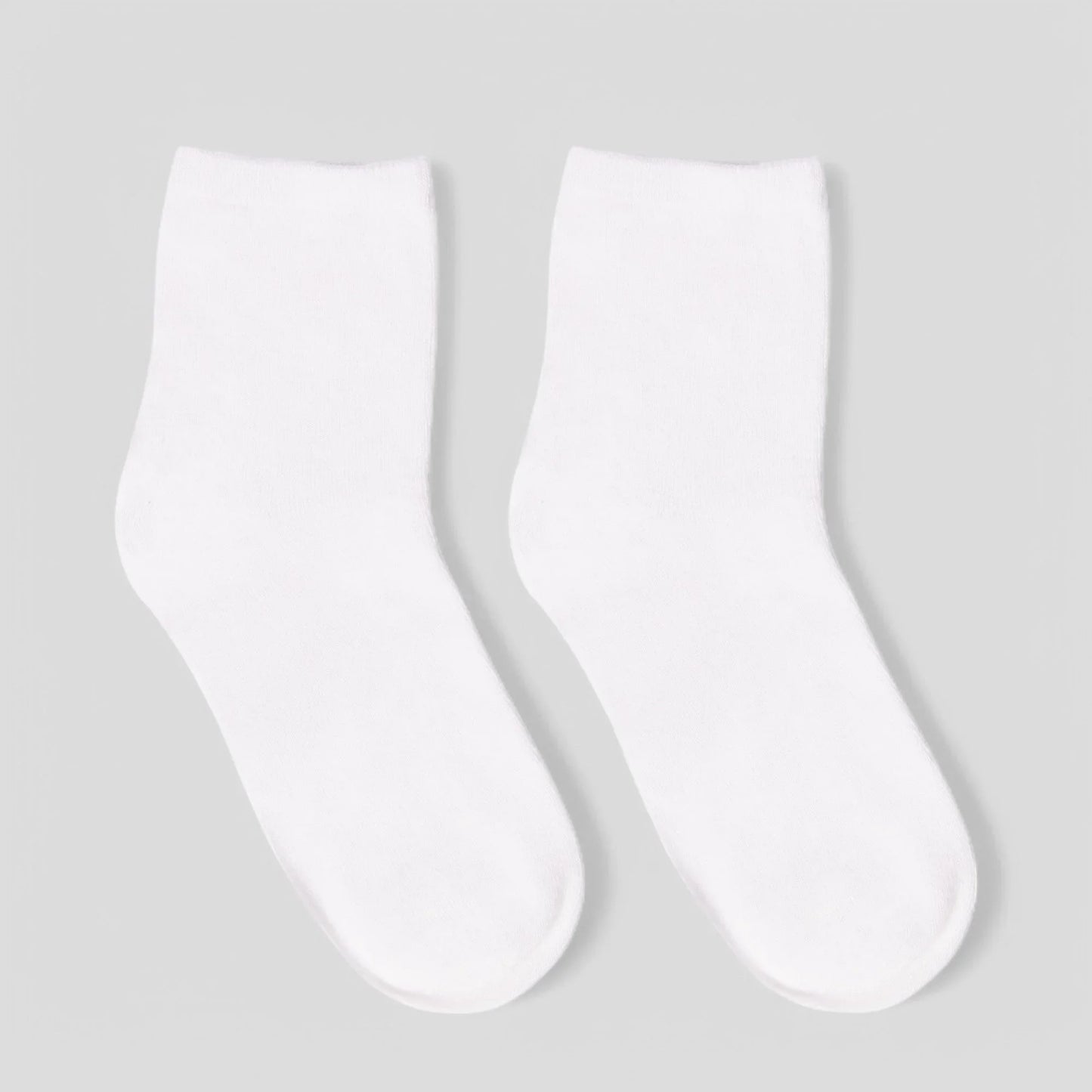 Pair of plain white sensory-friendly crew socks on light background