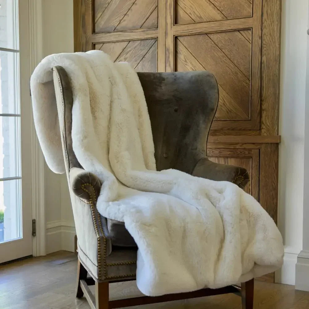 Plush vanilla faux fur weighted blanket draped over a cozy armchair in a home setting