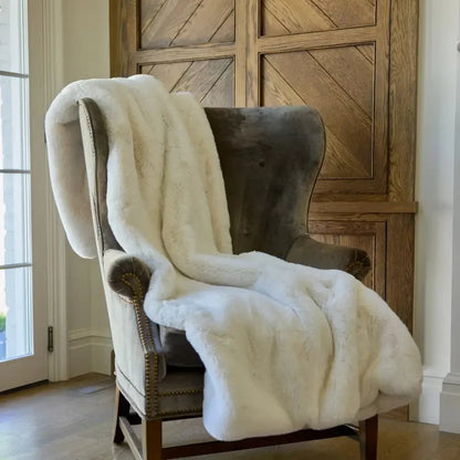 Plush vanilla faux fur weighted blanket draped over a cozy armchair in a home setting