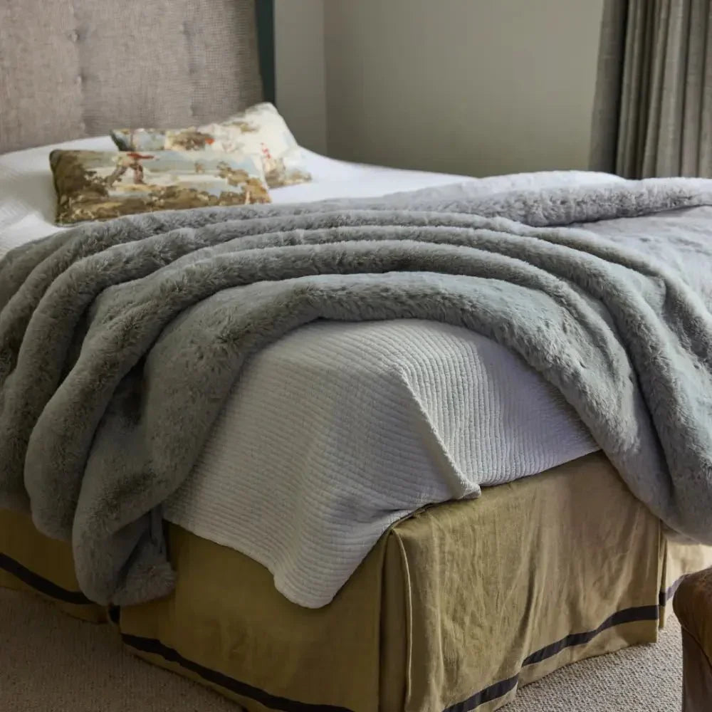 Soft grey weighted blanket draped on a neatly made bed in a cozy bedroom.