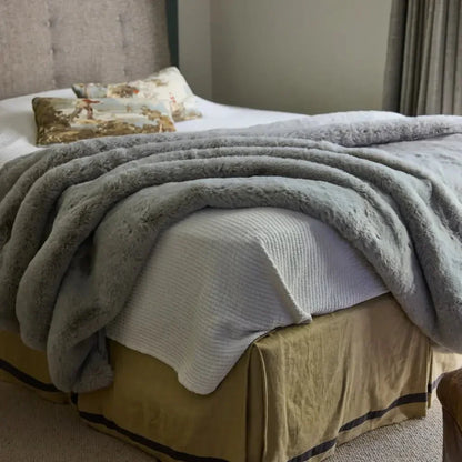 Soft grey weighted blanket draped on a neatly made bed in a cozy bedroom.
