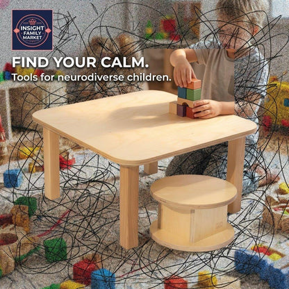 Child at sensory-friendly wooden table stacking colorful blocks, neurodiversity support tools