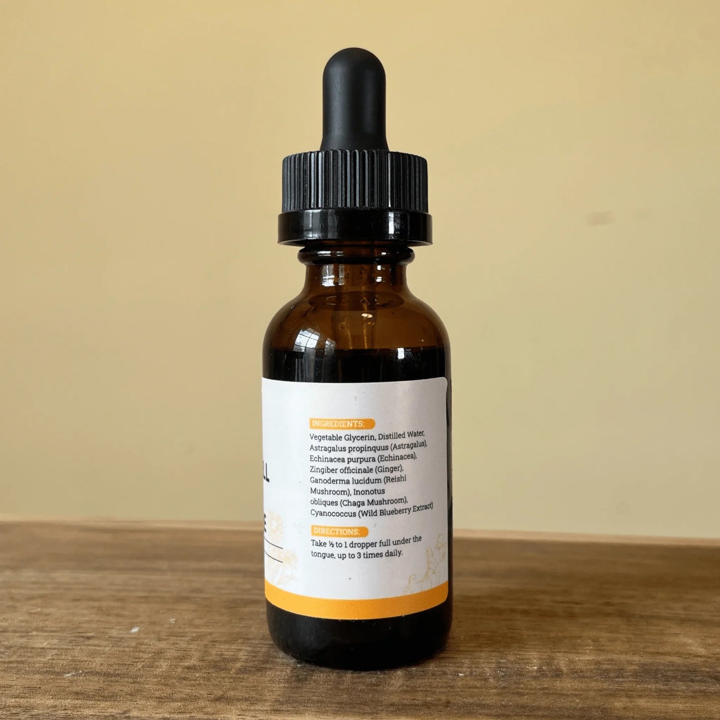 Amber glass dropper bottle with herbal tincture ingredients label on wooden surface