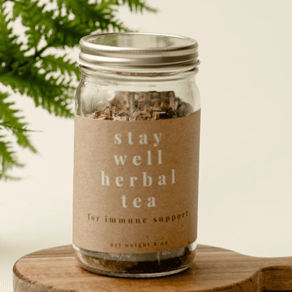 Glass jar of loose leaf herbal tea for immune support on wooden board with green leaves
