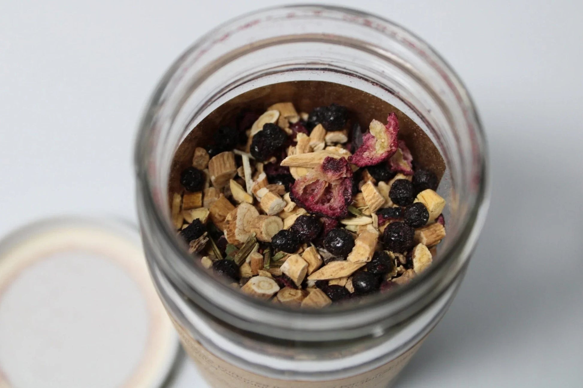 Loose leaf herbal tea blend with dried organic herbs and berries in a glass jar