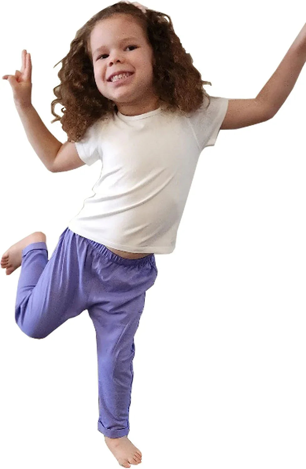Smiling child in sensory-friendly purple pants and white t-shirt jumping playfully