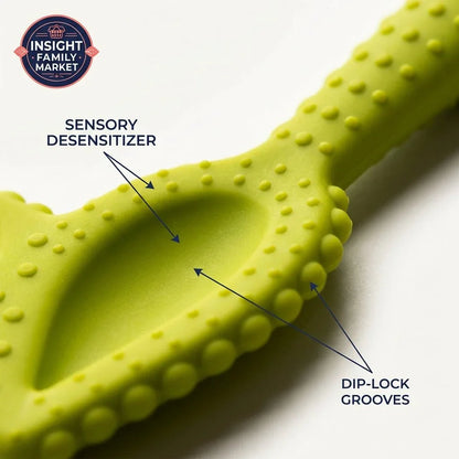 Close-up of green sensory feeding tool with textured bumps, labeled sensory desensitizer and dip-lock grooves.