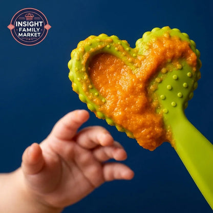 Baby reaching for green textured sensory oral tool with orange puree against blue background