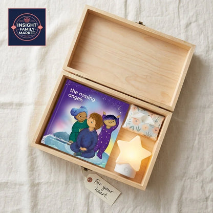 Wooden box with 'the missing angels' children's book, tissues, star night light, and a tag reading 'For your heart.'