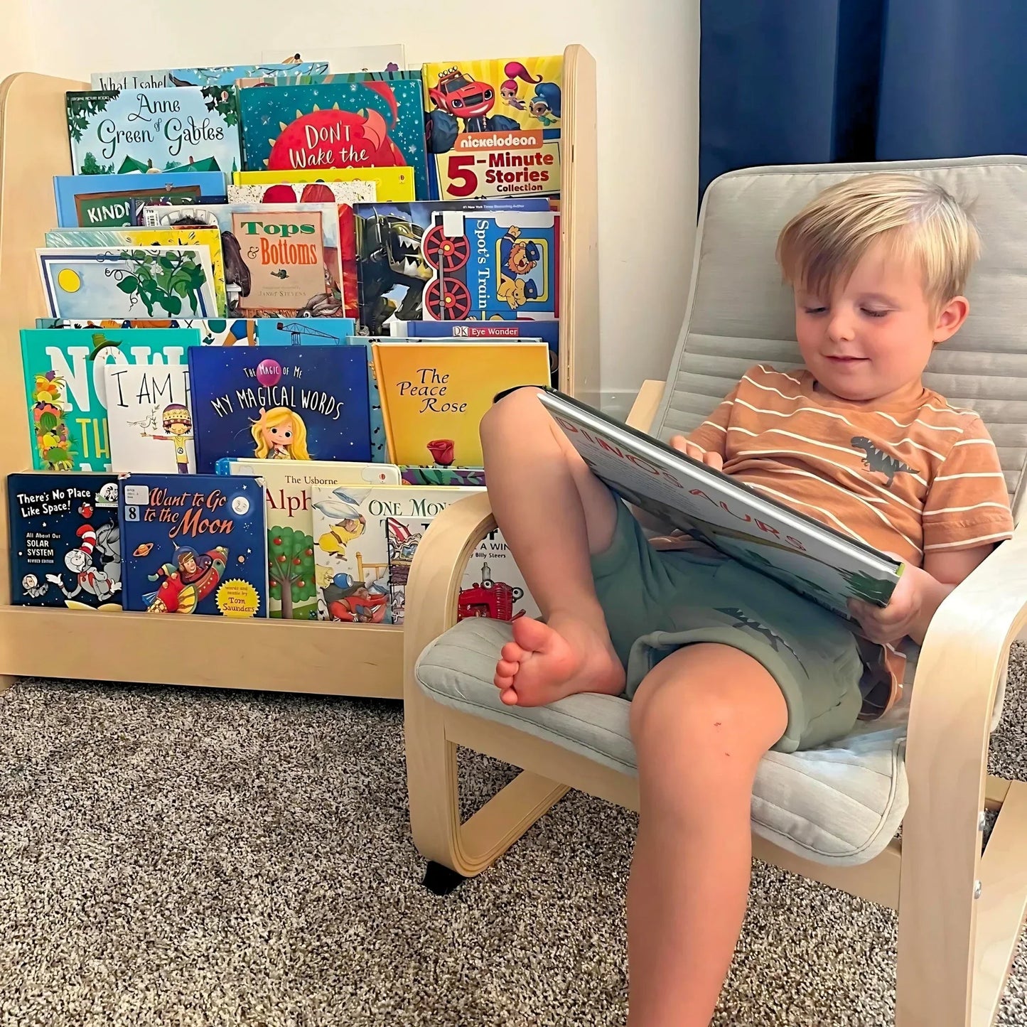 Child reading on chair beside Montessori bookshelf with colorful children's books