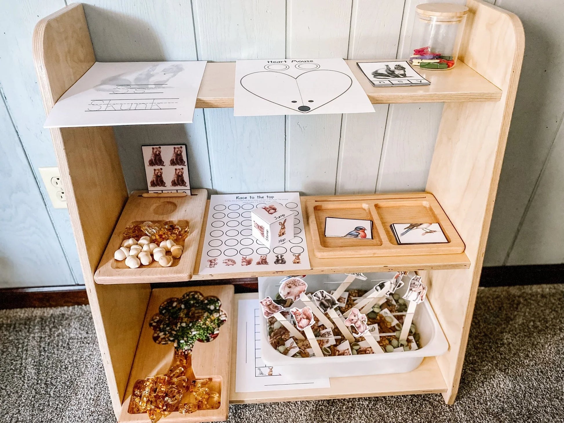 Tiered wooden toy shelf with sorting trays, learning cards, sensory and educational materials
