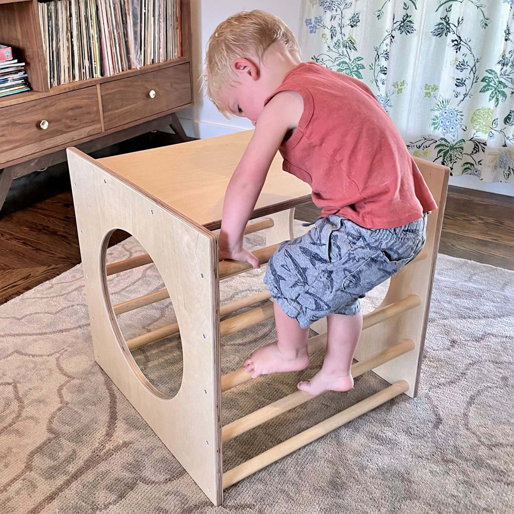 Child playing on a wooden climbing toy in a home setting
