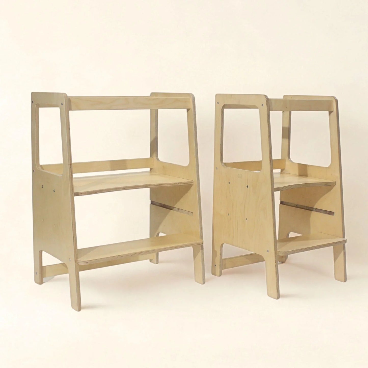 Two wooden toddler learning towers in different sizes on a neutral background.