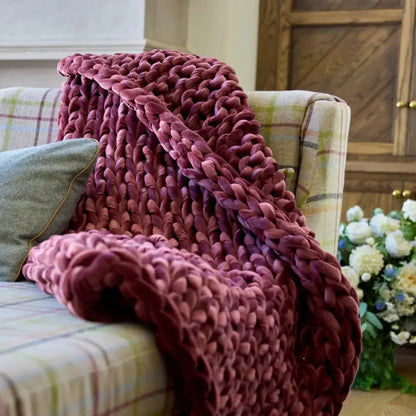 Chunky ruby velvet weighted blanket draped over a plaid sofa for cozy sensory support