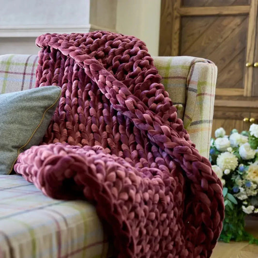 Chunky ruby velvet weighted blanket draped over a plaid sofa for cozy sensory support