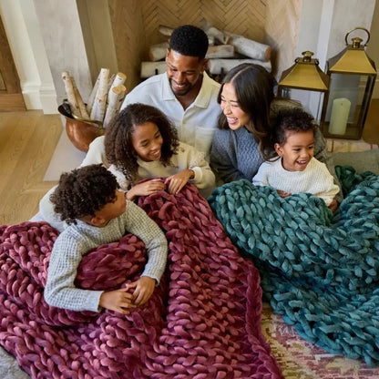 Smiling family relaxing with chunky velvet weighted blankets by the fireplace