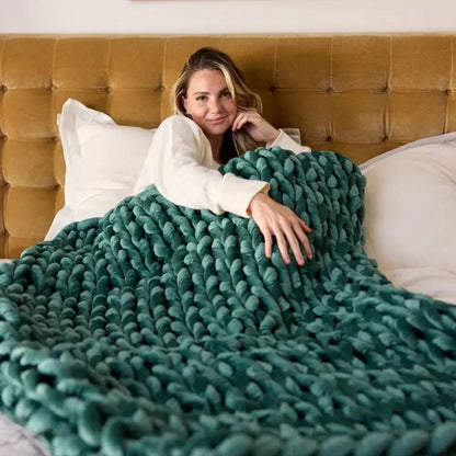 Woman relaxing in bed with an emerald green chunky velvet weighted blanket
