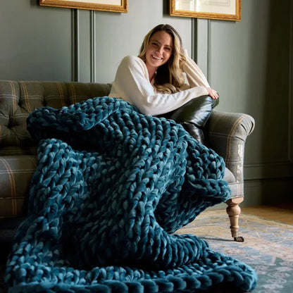 Woman relaxing on sofa with chunky sapphire velvet weighted blanket, cozy sensory support