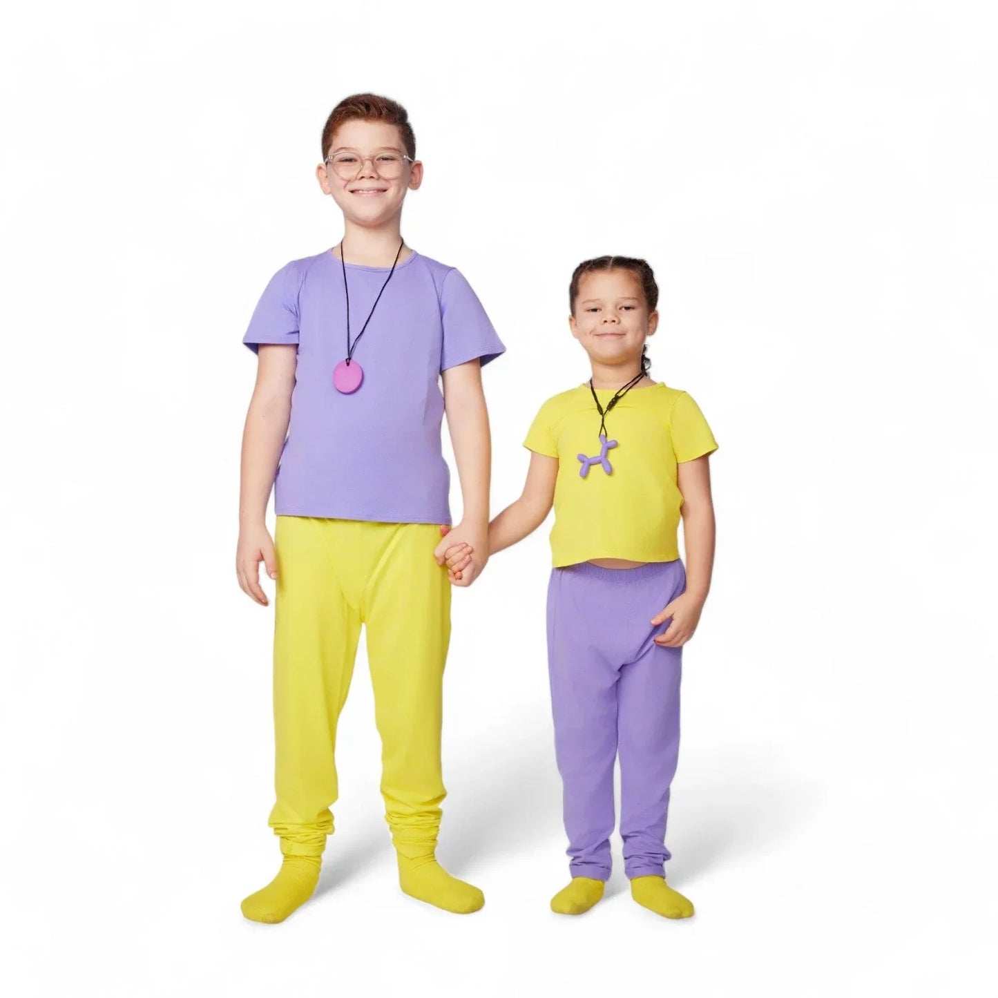 Two kids in yellow and purple sensory-friendly clothing holding hands on white background