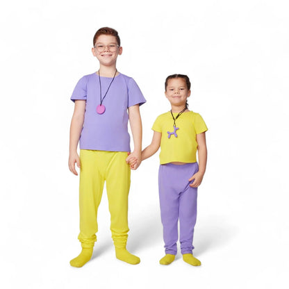 Two kids in yellow and purple sensory-friendly clothing holding hands on white background