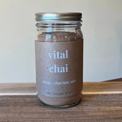 Glass jar of vital chai cacao and chai latte mix on a wooden surface
