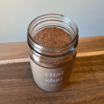 Jar of Vital Chai energizing adaptogenic cacao chai latte mix on wooden surface