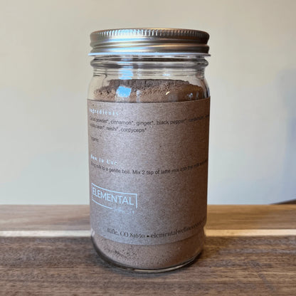 Glass jar of cacao chai latte mix with brown label on wooden surface